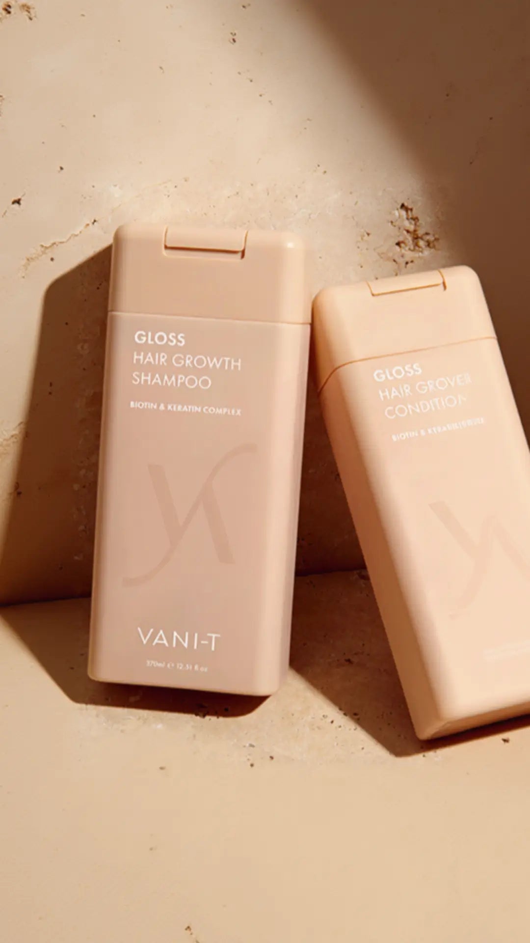 VANI-T Gloss Hair Growth šampūnas ir kondicionierius šviesiai smėlio spalvos pakuotėse ant neutralaus fono, apšviesti šilta natūralia šviesa
